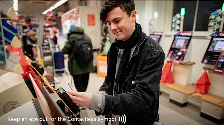 Young man in a shop paying for shopping Contactless with his card